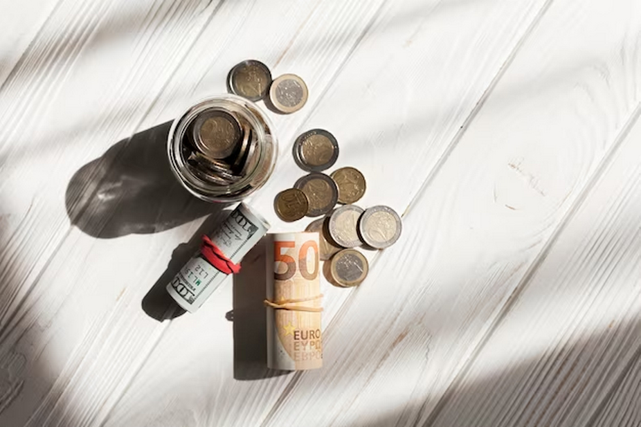 Rolled dollar bills, scattered coins, and coins inside a jar.